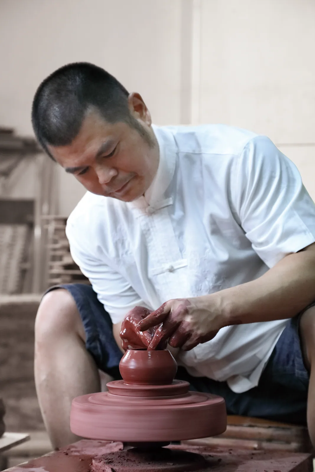 Close view of Zhang Jincai shaping red clay at the wheel