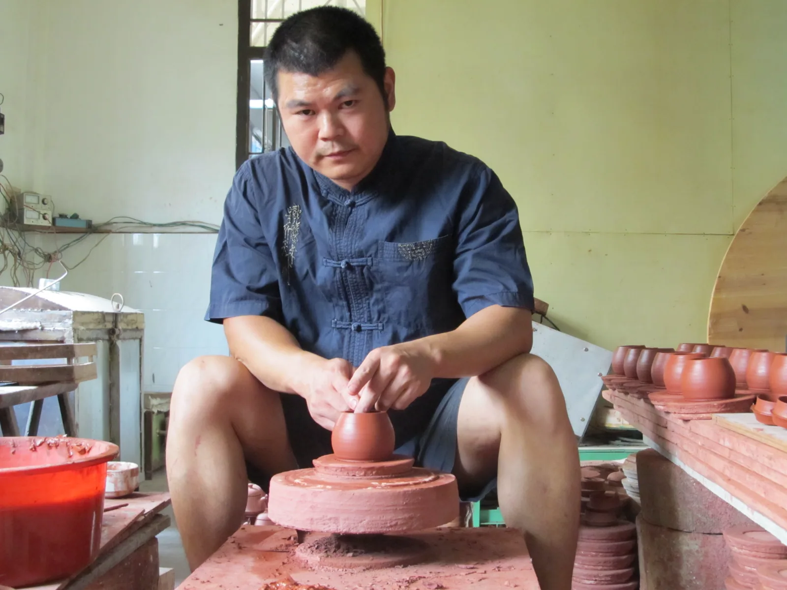 Zhang Jincai forming a red-clay vessel at his workshop wheel